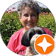 Smiling woman with gray hair holding a small black and white dog outdoors.